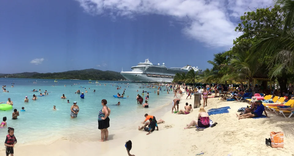Palm-lined Mahogany Beach with a cruise ship behind the bay