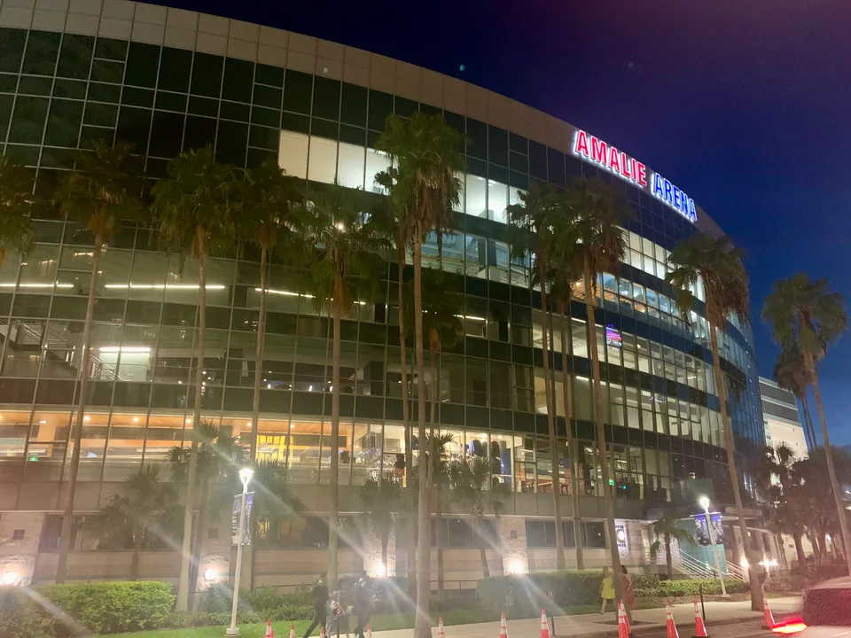 Illuminated curved arena exterior at night, with its former Amalie Arena name visible