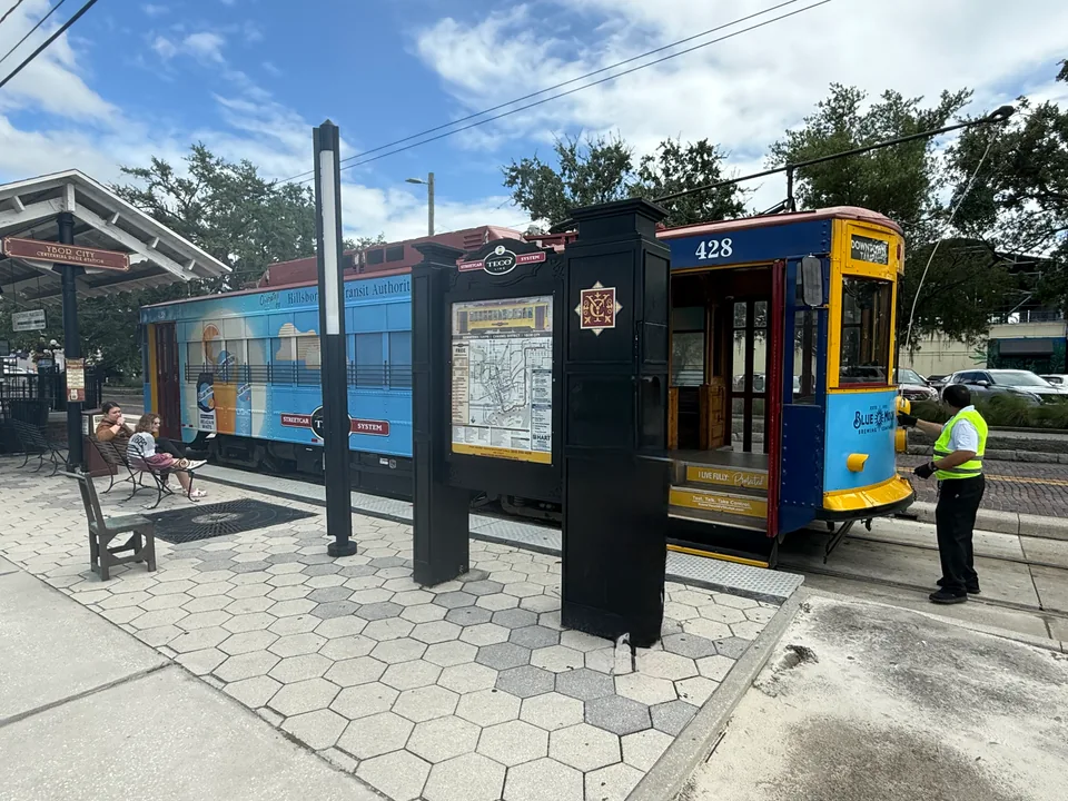 Yellow and blue TECO Line Streetcar beside a covered stop